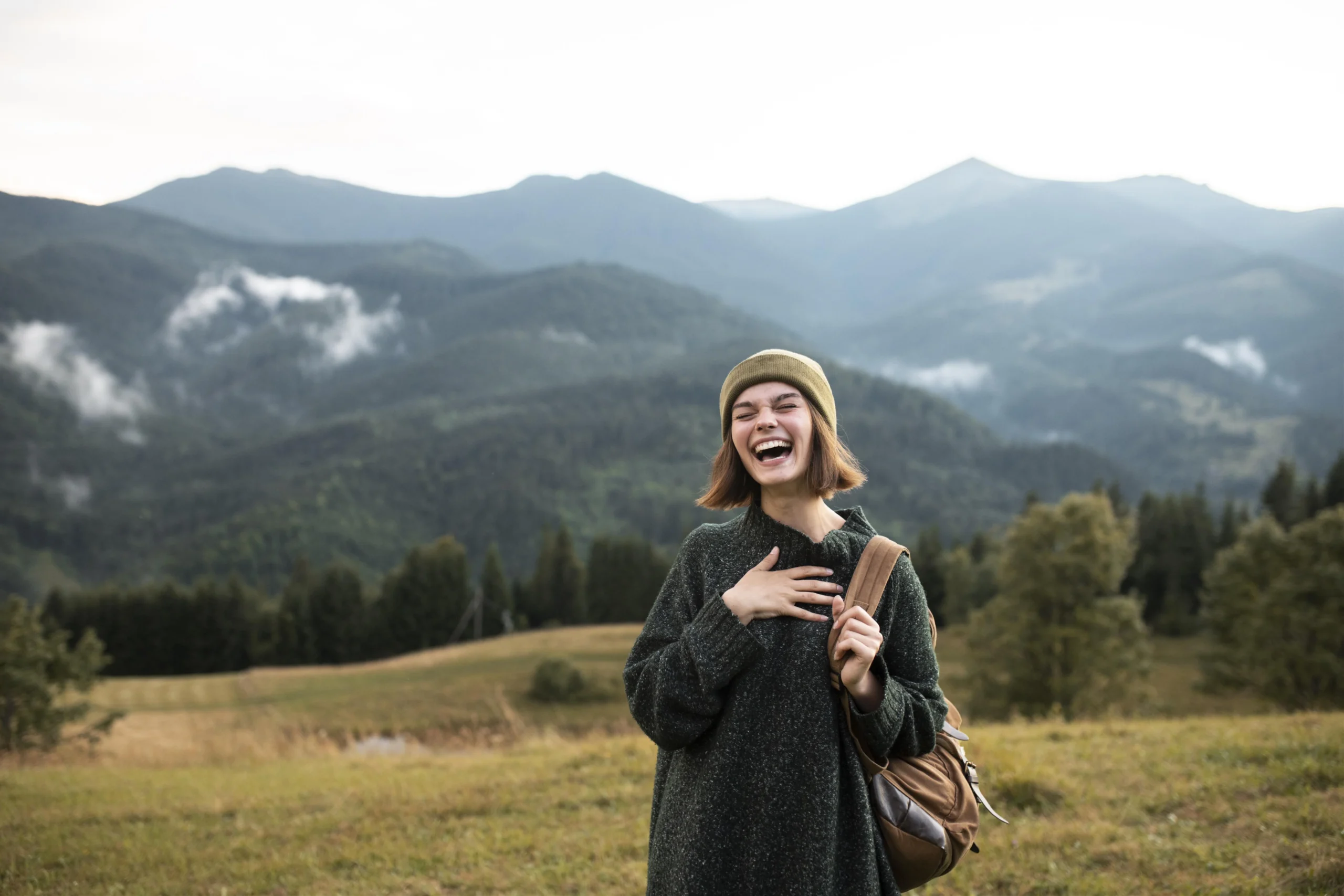 Femme au milieu de la nature et des montagnes qui rigole, heureuse